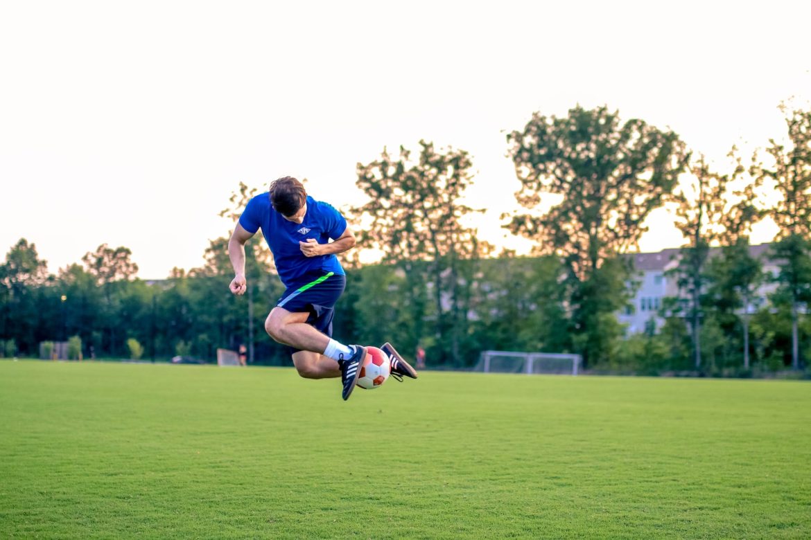 Leidenschaftlicher Mann genießt eine Partie Fußball, symbolisiert Sport als eine der kreativen Geschenkideen für den Mann