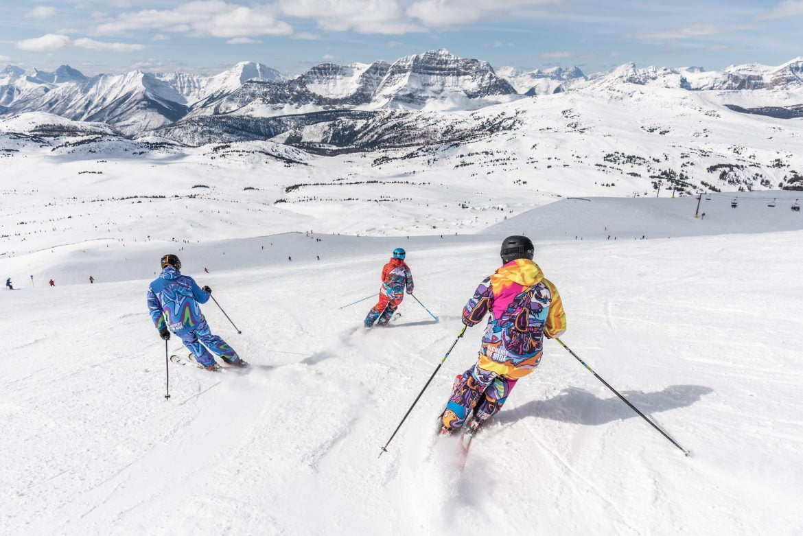Drei Skifahrer fahren eine Piste herunter, genießen den frischen Schnee und verkörpern die idealen Geschenkideen für Skifahrer, die das Abenteuer lieben.